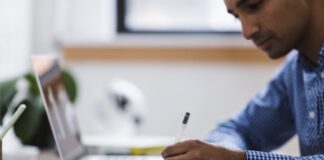 Adjectives and adverbs in journalism Man writing on notepad. Image by NegativeSpace released via Creative Commons