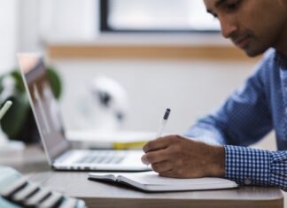 Adjectives and adverbs in journalism Man writing on notepad. Image by NegativeSpace released via Creative Commons