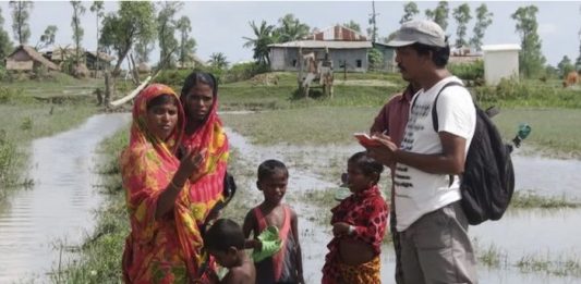 Climate change journalist Rafiqul Islam Montu interviewing flooding survivors