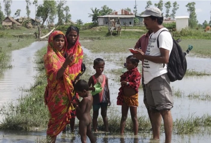 Climate change journalist Rafiqul Islam Montu interviewing flooding survivors